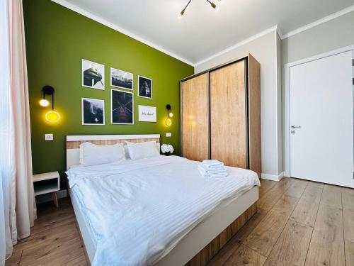 1 dormitorio con 1 cama grande y pared verde en Grand Turan Business 2-Room Apartament's, en Astana