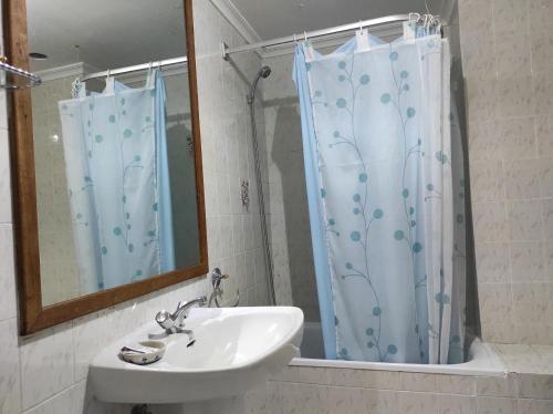 a bathroom with a sink and a shower curtain at TANISHOSTALRESTAURANTE in Riaño