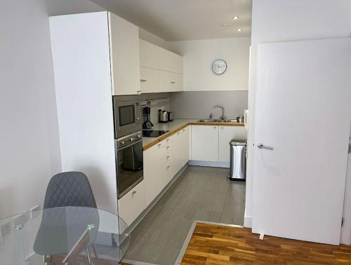 cocina con armarios blancos y mesa de cristal en Manchester's Prime - Luxurious 1-Bed Flat en Mánchester