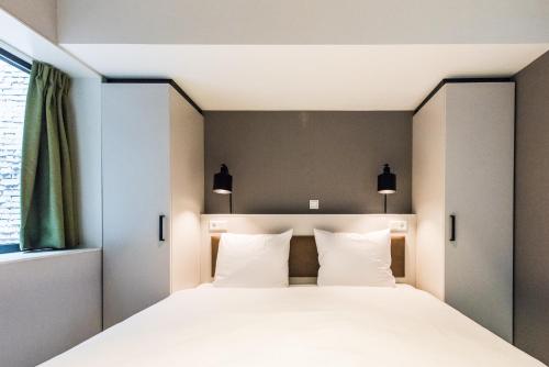 - une chambre avec un grand lit et des oreillers blancs dans l'établissement YAYS Amsterdam East by Numa, à Amsterdam