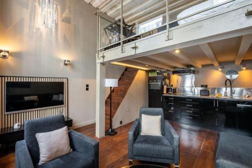 un salon avec deux chaises et un escalier dans l'établissement Paris 1er - Magnifique duplex, à Paris