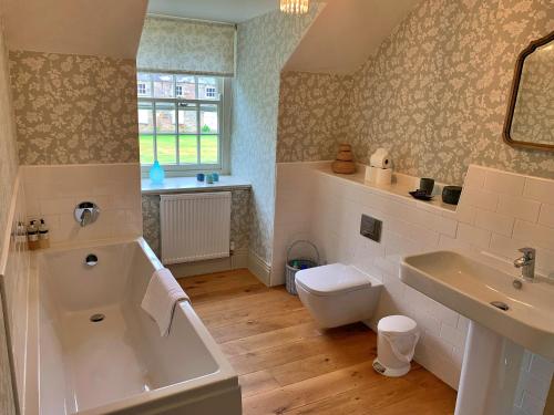 a bathroom with a tub and a toilet and a sink at Finest Retreats - Ingleby Manor - Courtyard Cottage in Great Ayton