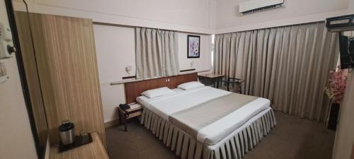 Un dormitorio con una gran cama blanca y una ventana en Hotel Swaroop, en Pune