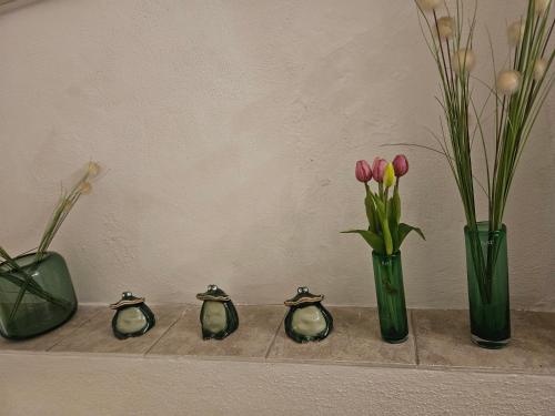 trzy wazy z kwiatami na półce w obiekcie Hotel Andreasstuben w mieście Weißenburg in Bayern