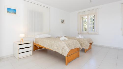 a white bedroom with two beds and a window at GERANIS in Llafranc