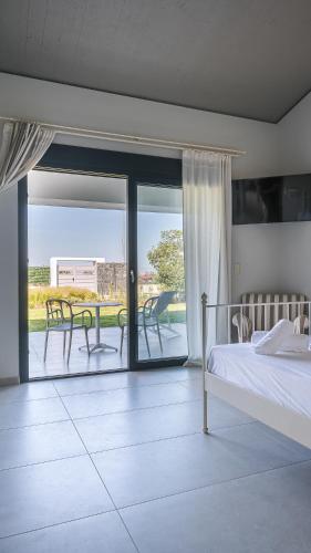 a bedroom with a bed and a balcony with a table and chairs at Electra BeachFront Suites, Nea Irakleia in Nea Irakleia