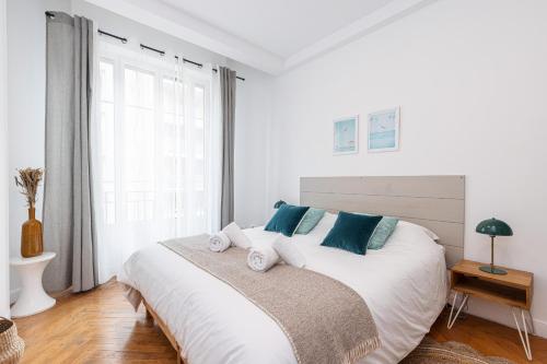 une chambre blanche avec un grand lit avec des oreillers bleus dans l'établissement Cosy 1 Bdr near Garibaldi Square, à Nice