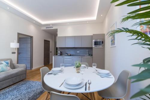 une cuisine et un salon avec une table et des chaises blanches dans l'établissement Brand New 1 Bdr Place du Pin, à Nice