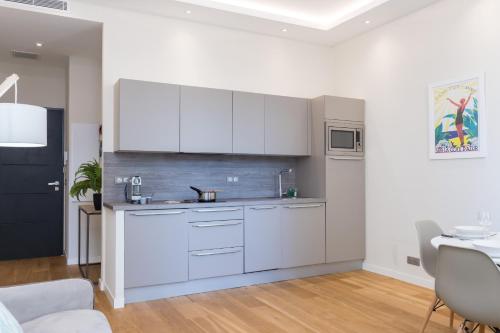 une cuisine avec des armoires blanches et une table dans une pièce dans l'établissement Brand New 1 Bdr Place du Pin, à Nice