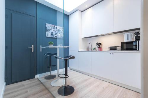 une cuisine avec des placards bleus et un comptoir avec des tabourets dans l'établissement Magenta Square Central 1 Bdr with AC, à Nice