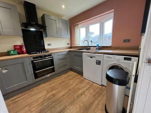 a kitchen with white cabinets and a washer and sink at Harmony House - 4 Doubles, Free Wi-fi, Parking in Walsall