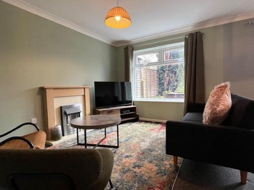 a living room with a couch and a table and a tv at Harmony House - 4 Doubles, Free Wi-fi, Parking in Walsall