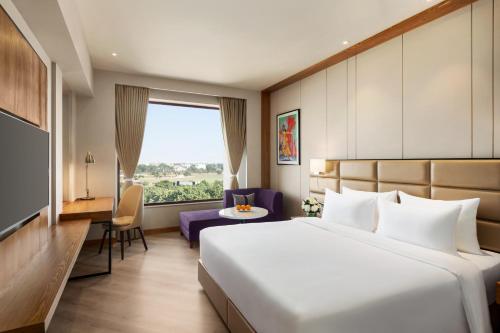 a hotel room with a bed and a window at Ramada Encore by Wyndham Amritsar Airport in Amritsar