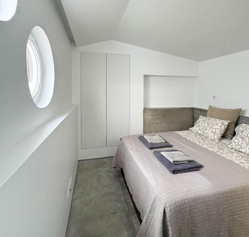 a white bedroom with a bed and a window at Casa Pátio Boa Vista 4 in Setúbal