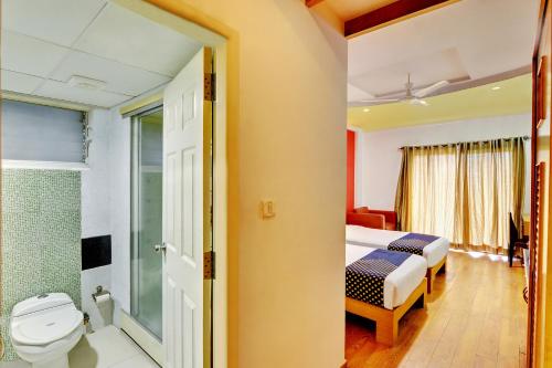 a bathroom with a bed and a toilet in a room at Hotel Twin Tulips HSR Layout in Bangalore