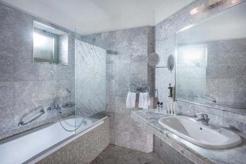 a bathroom with a tub and a sink and a bath tub at Bella Beach Hotel in Hersonissos
