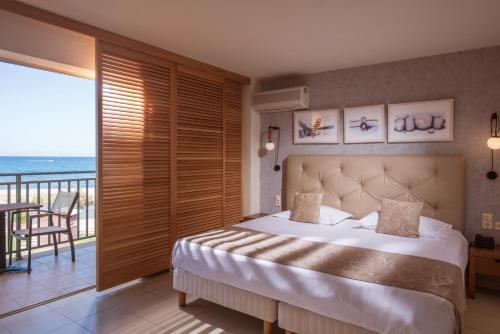 a bedroom with a bed with a view of the ocean at Bella Beach Hotel in Hersonissos