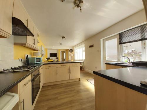 uma grande cozinha com armários brancos e uma grande janela em Beautiful Two Bedroom ground floor apartment em Swansea