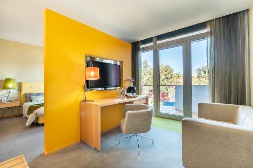 a hotel room with a yellow wall and a desk with a television at Hotel Santa Margarida in Oleiros