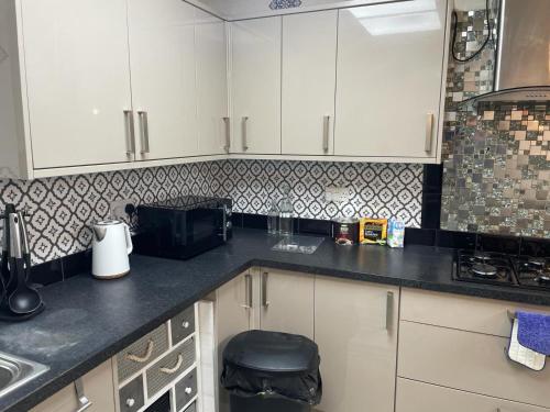 une cuisine avec des placards blancs et un comptoir noir dans l'établissement Rahal Compton, à Londres