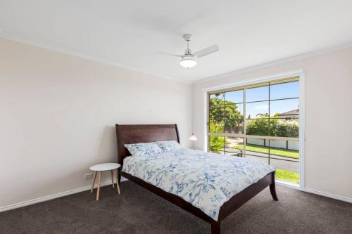 a white bedroom with a bed and a window at Beautiful 3 bedroom house with Corio Bay view at heart of Clifton Springs in Clifton Springs