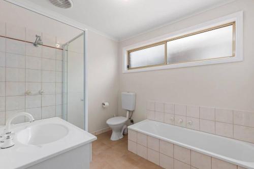 a bathroom with a tub and a sink and a toilet at Beautiful 3 bedroom house with Corio Bay view at heart of Clifton Springs in Clifton Springs