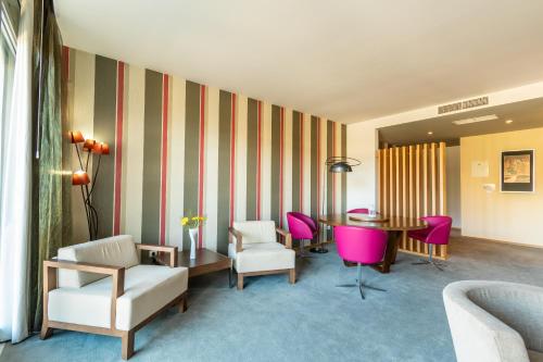 a hotel room with a table and pink chairs at Hotel Santa Margarida in Oleiros