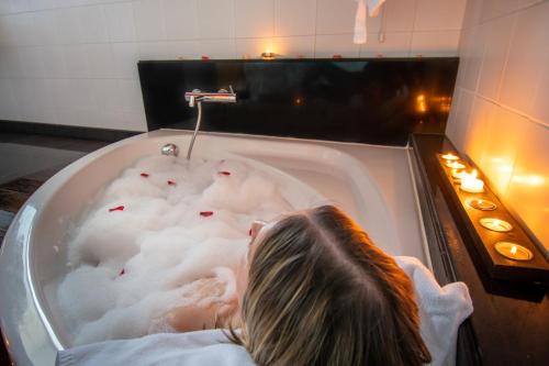 a little girl laying in a bathtub filled with foam at Hotel Santa Margarida in Oleiros