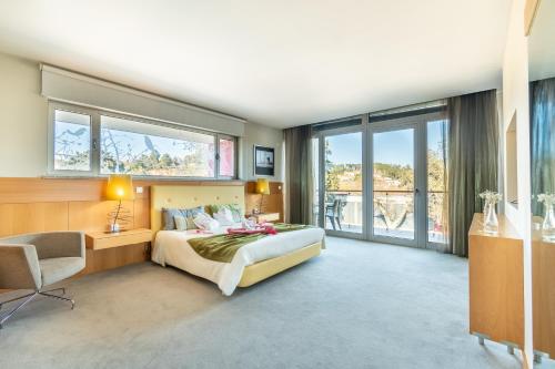 a bedroom with a bed and a desk and windows at Hotel Santa Margarida in Oleiros