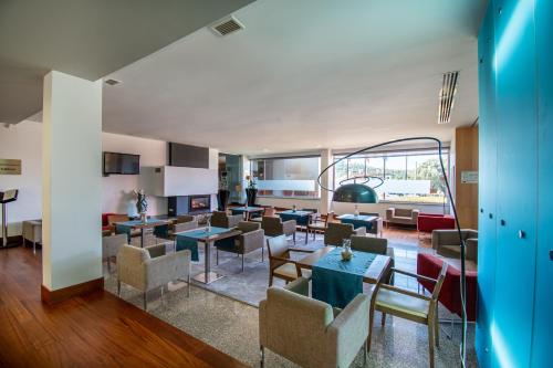 a lobby with tables and chairs in a building at Hotel Santa Margarida in Oleiros