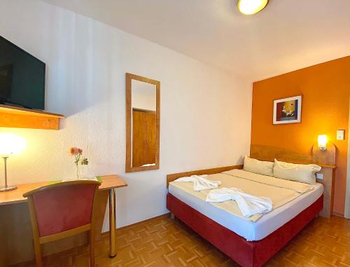 a hotel room with a bed and a desk and a chair at Hotel Gasthof Rose in Günzburg