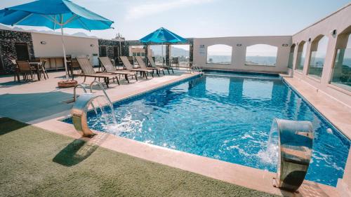 a swimming pool with tables and chairs and an umbrella at My Hotel by Trend in Aqaba