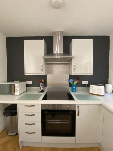 a kitchen with white cabinets and a stove top oven at Neat Retreat-Cilfynyd-Pontypridd in Pontypridd