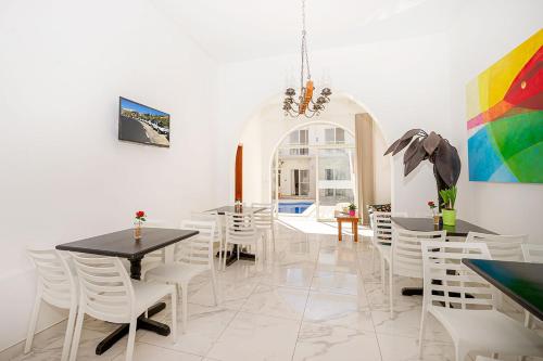 a dining room with white tables and white chairs at Phase Guesthouse in Xewkija