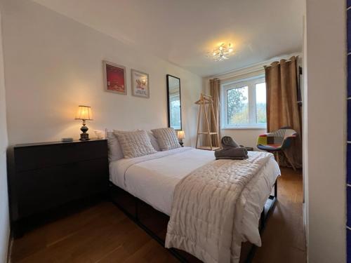 1 dormitorio con cama, escritorio y ventana en Great 2 bedrooms apartment 15 mins from the centre, en Londres