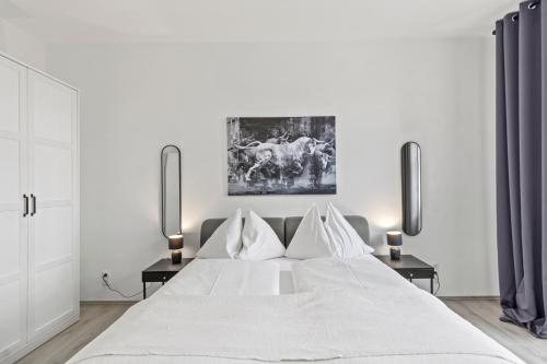 a white bedroom with a large white bed with two lamps at StayEasy Apartments St. M. 2 