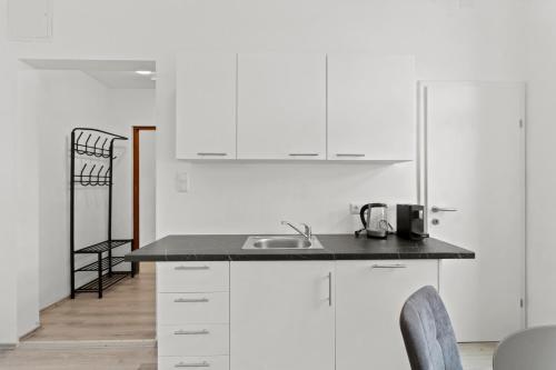 a kitchen with white cabinets and a sink and chairs at FarawayHomes Studio Sankt Michael #5 in Liesingthal