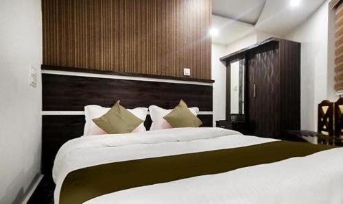 FabHotel Prime Suloka Towers في كوشالناغار: غرفة نوم بسرير كبير عليها شراشف ووسائد بيضاء