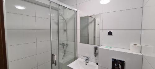 La salle de bains est pourvue d'une douche, d'un lavabo et d'un miroir. dans l'établissement Motel i Restauracja "Pod Basztą", à Nagłowice
