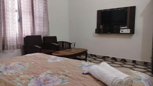 a bedroom with a bed and a flat screen tv at Baikunth Homes in Dalhousie