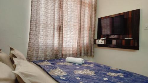 a bedroom with a bed with a tv on the wall at Baikunth Homes in Dalhousie