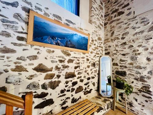 Cette chambre est dotée d'un mur en pierre avec un miroir et un banc. dans l'établissement Au pied du château- Parking Wifi jardin - CLG Savoie, à Fréterive