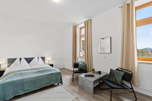 a white bedroom with a bed and a chair at FarawayHomes Studio Sankt Michael #10 in Sankt Michael in Obersteiermark