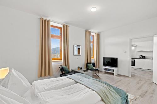 a white bedroom with a bed and a kitchen at FarawayHomes Studio Sankt Michael #10 in Sankt Michael in Obersteiermark