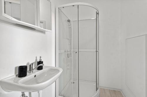 La salle de bains blanche est pourvue d'un lavabo et d'une douche. dans l'établissement StayEasy Apartments Sankt Michael #1, à Sankt Michael in Obersteiermark