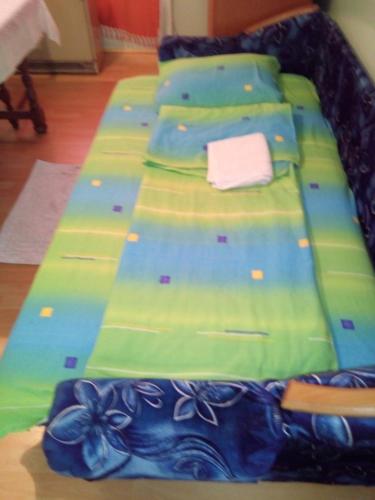 a bed with a blue and green comforter at Soba Macva in Banja Koviljača