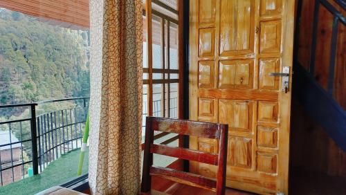 a wooden door with a chair in front of a balcony at Baikunth Homes in Dalhousie