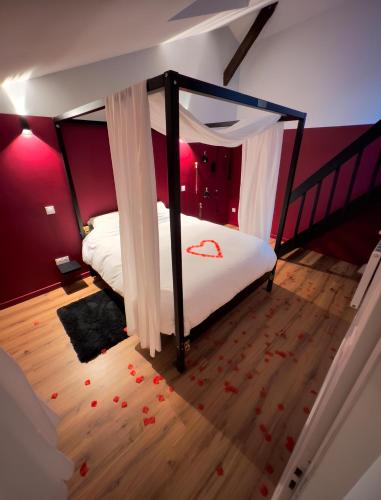 une chambre avec un lit à baldaquin dans l'établissement 50 Nuances d'Amour - Jacuzzi / Massage / Cinéma, à Moirans
