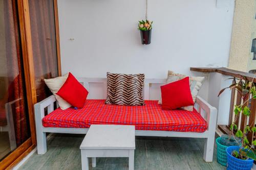 eine Bank mit roten Kissen auf einer Veranda in der Unterkunft Casa bella Beach apartment in Ukunda