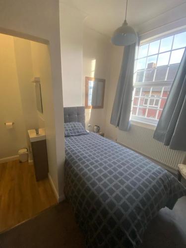 a bedroom with a bed with a blue comforter and a window at The Bowmans in Howden